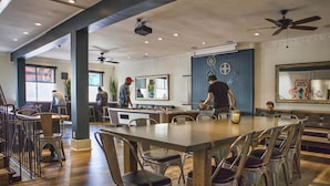 Een ruim restaurant met hoge plafonds, modern meubilair en diverse zitmogelijkheden, waaronder tafels en stoelen.