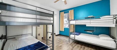 Un dormitorio con literas, ventilador de techo y ventana con cortinas.