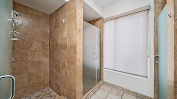 A bathroom with a shower, a glass door, and a tiled floor.