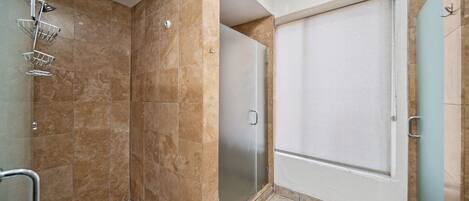 Un baño con ducha, puerta de vidrio y suelo de baldosas.