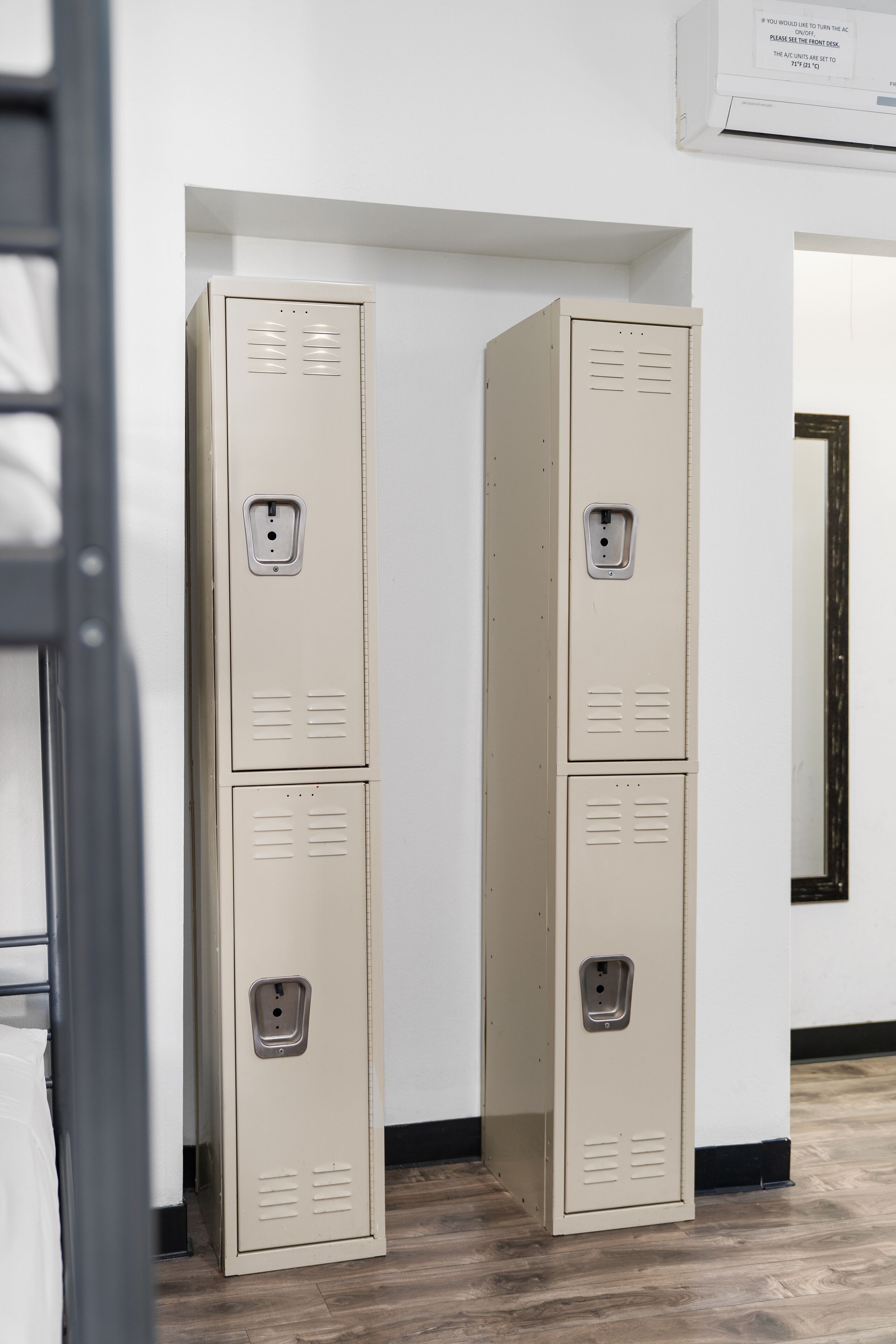 Two beige lockers in a hallway with a wooden floor and a white wall.