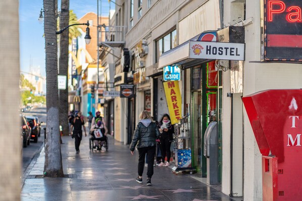 A street with a sign for a hostel, a market, and an ATM. - Samesun Hollywood - Hostel (Los Angeles)