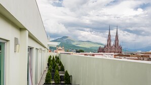 A hotel balcony with a view of a large cathedral and mountains in the background.