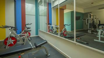 Un gimnasio con bicicletas estáticas, una caminadora y máquinas de pesas.