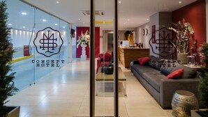 A hotel reception area with a modern design, featuring a reception desk, seating area, and glass walls.