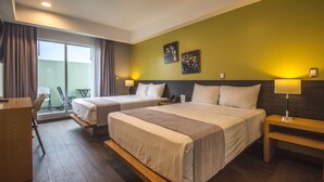 A hotel room with two beds, a desk, and a balcony with a chair.
