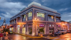 A hotel with a prominent sign, multiple storefronts, and a street view.
