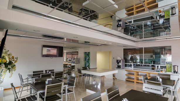 A modern, multi-level dining area with glass partitions, metal furniture, and a central island.