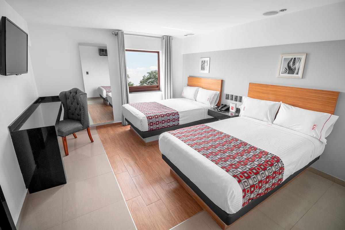 Une chambre d’hôtel avec deux lits, un bureau, une chaise et un téléviseur.