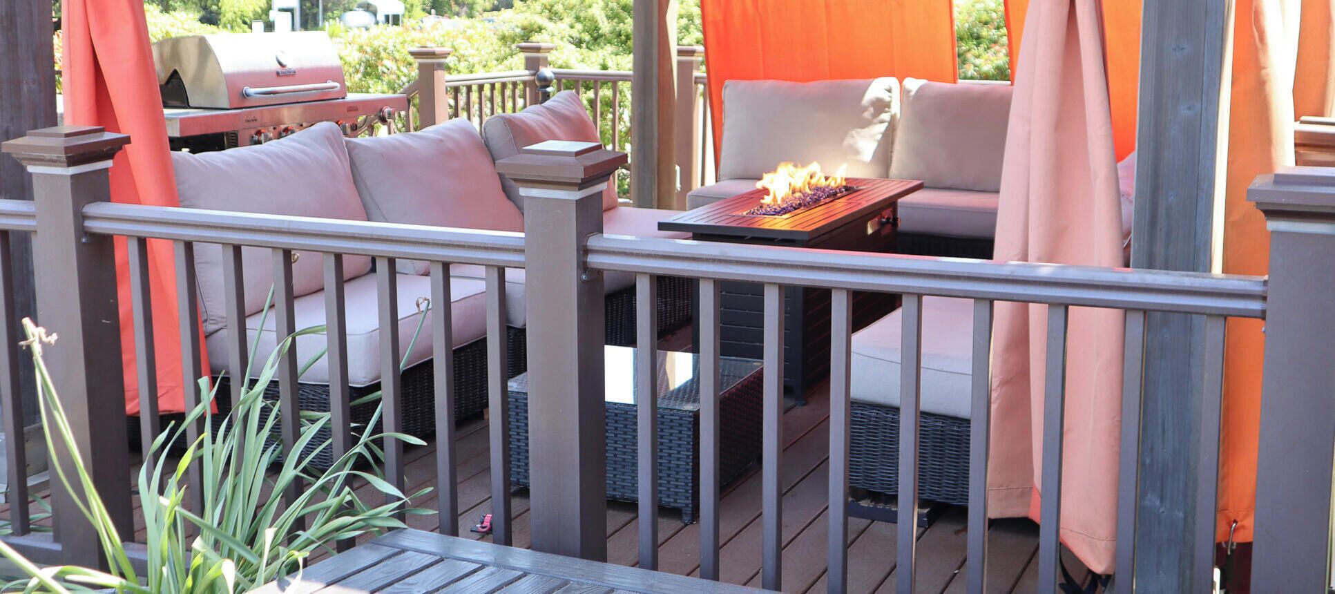 A deck with outdoor furniture, a grill, and a fire feature.
