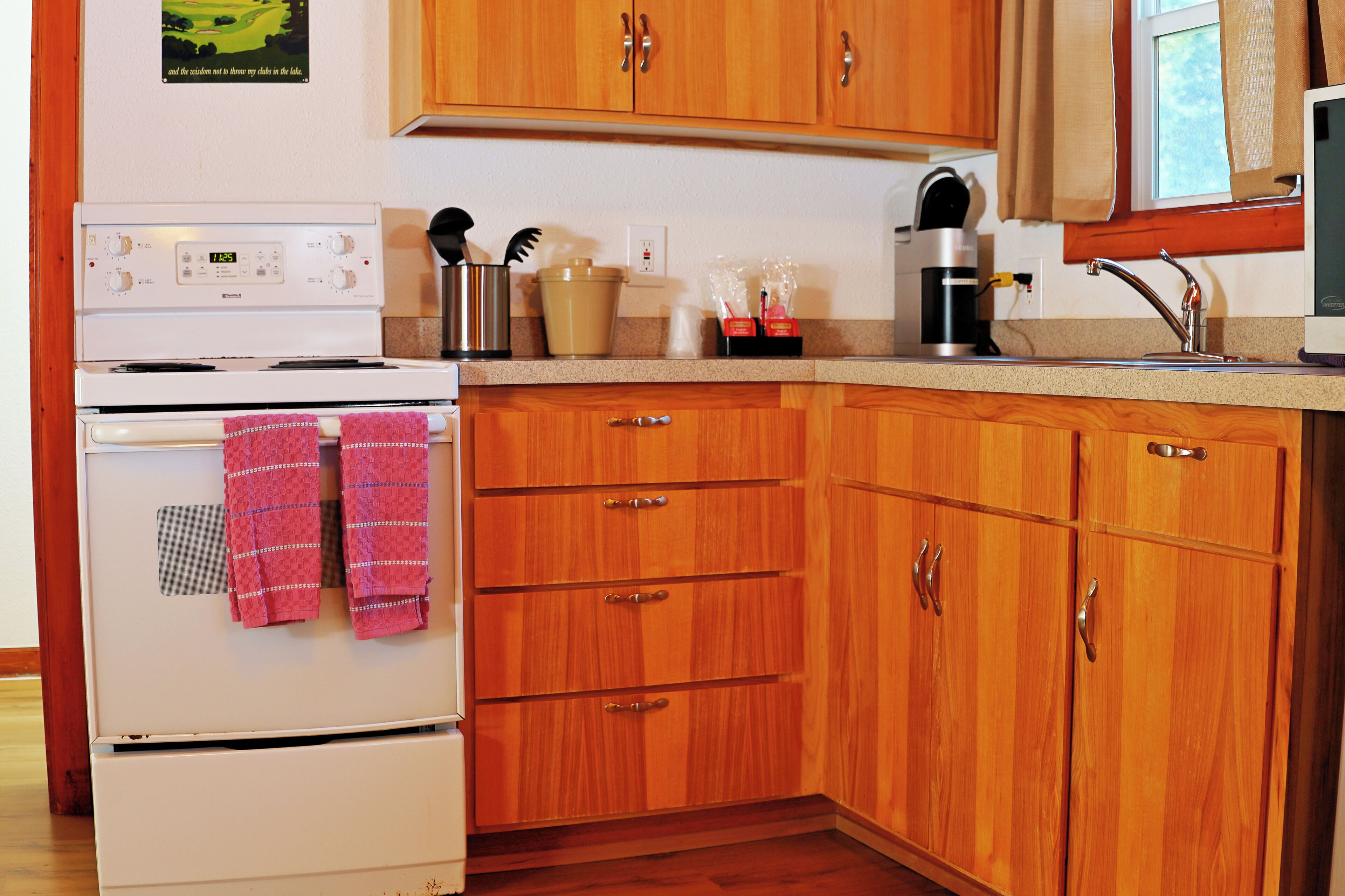 Une cuisine avec des meubles de rangement en bois, une cuisinière et un évier.