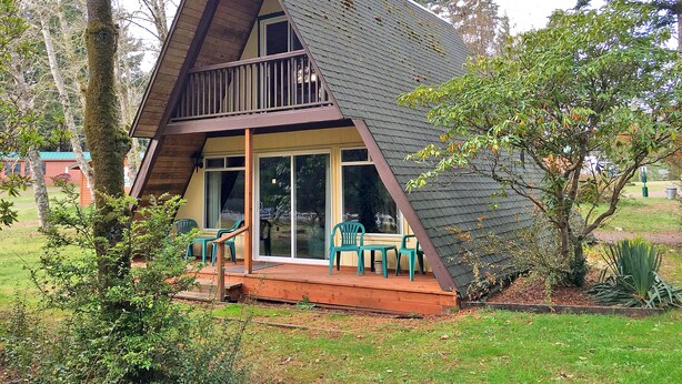 A small, A-frame cabin with a balcony and a porch area. - Park Motel and Cabins (Florence)