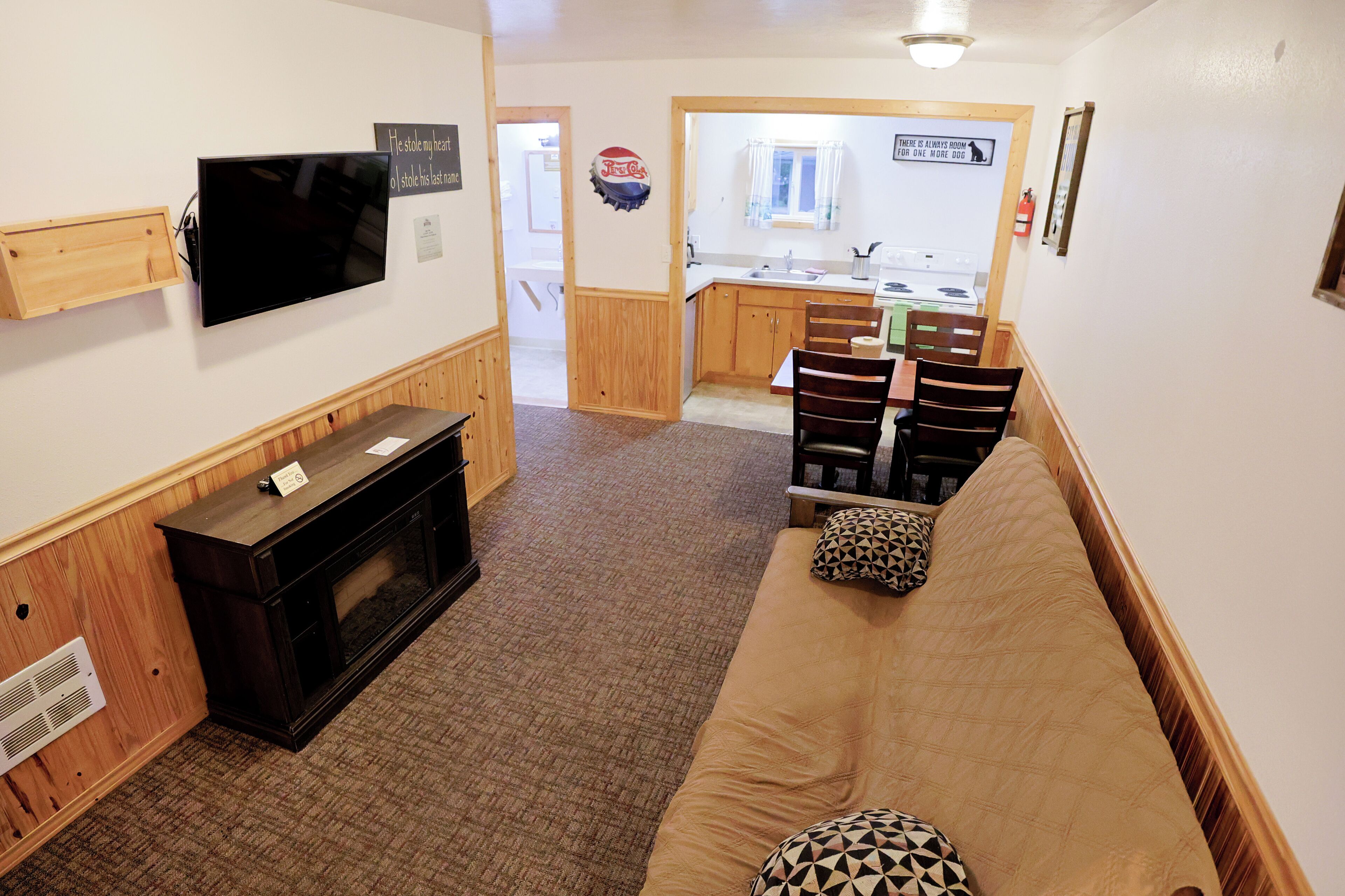 A living room with a TV, wooden entertainment unit, and a sofa with patterned cushions.