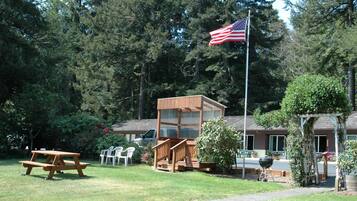 Uma mesa de piquenique, um gazebo de madeira e um mastro com a bandeira americana.
