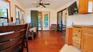 A room with a wooden bench, a chair, a television, and a sliding glass door leading to an outdoor area. - Park Motel and Cabins (Florence)