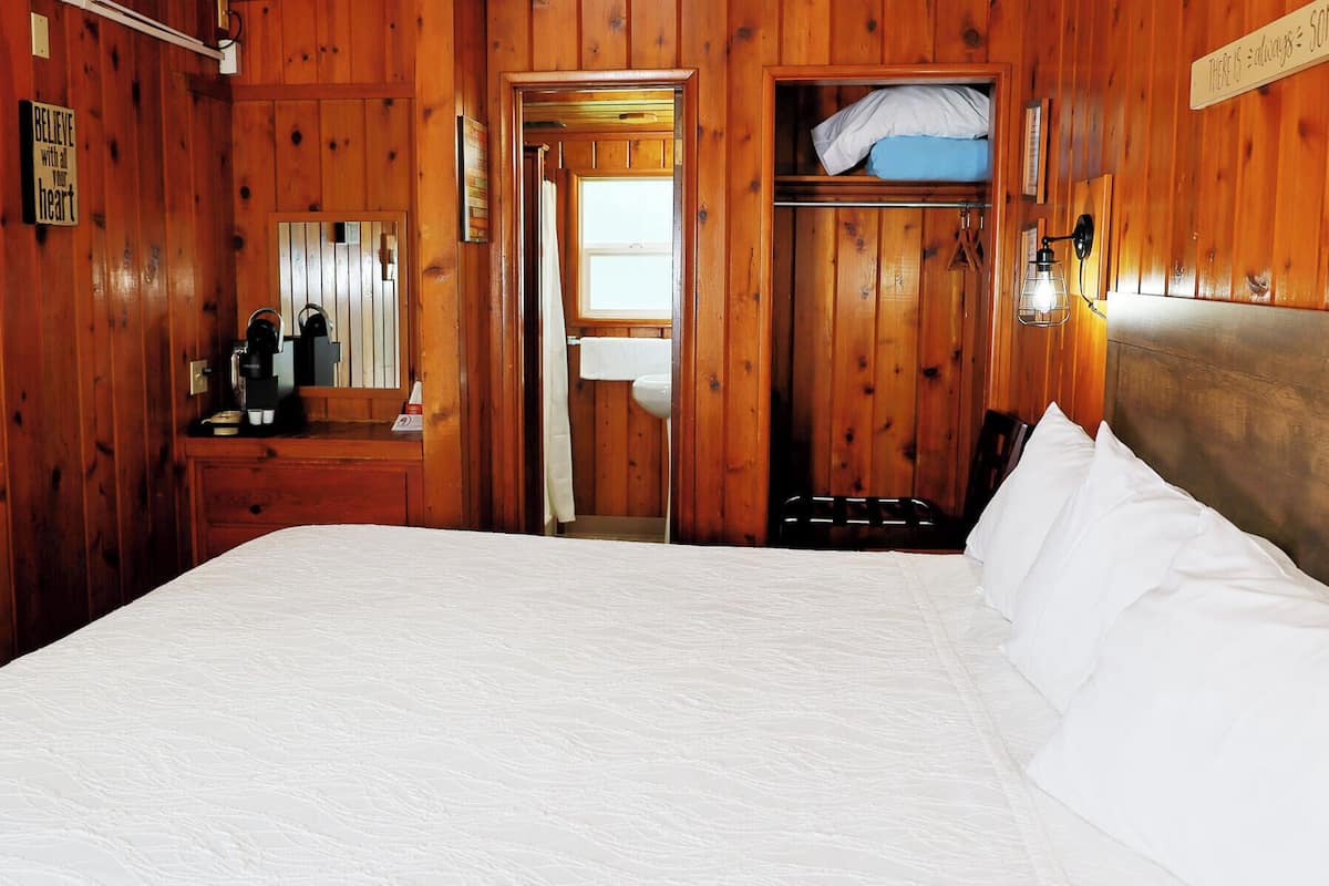 A wooden room with a bed, a dresser, a mirror, and a sign that says 'Believe with all your heart'.