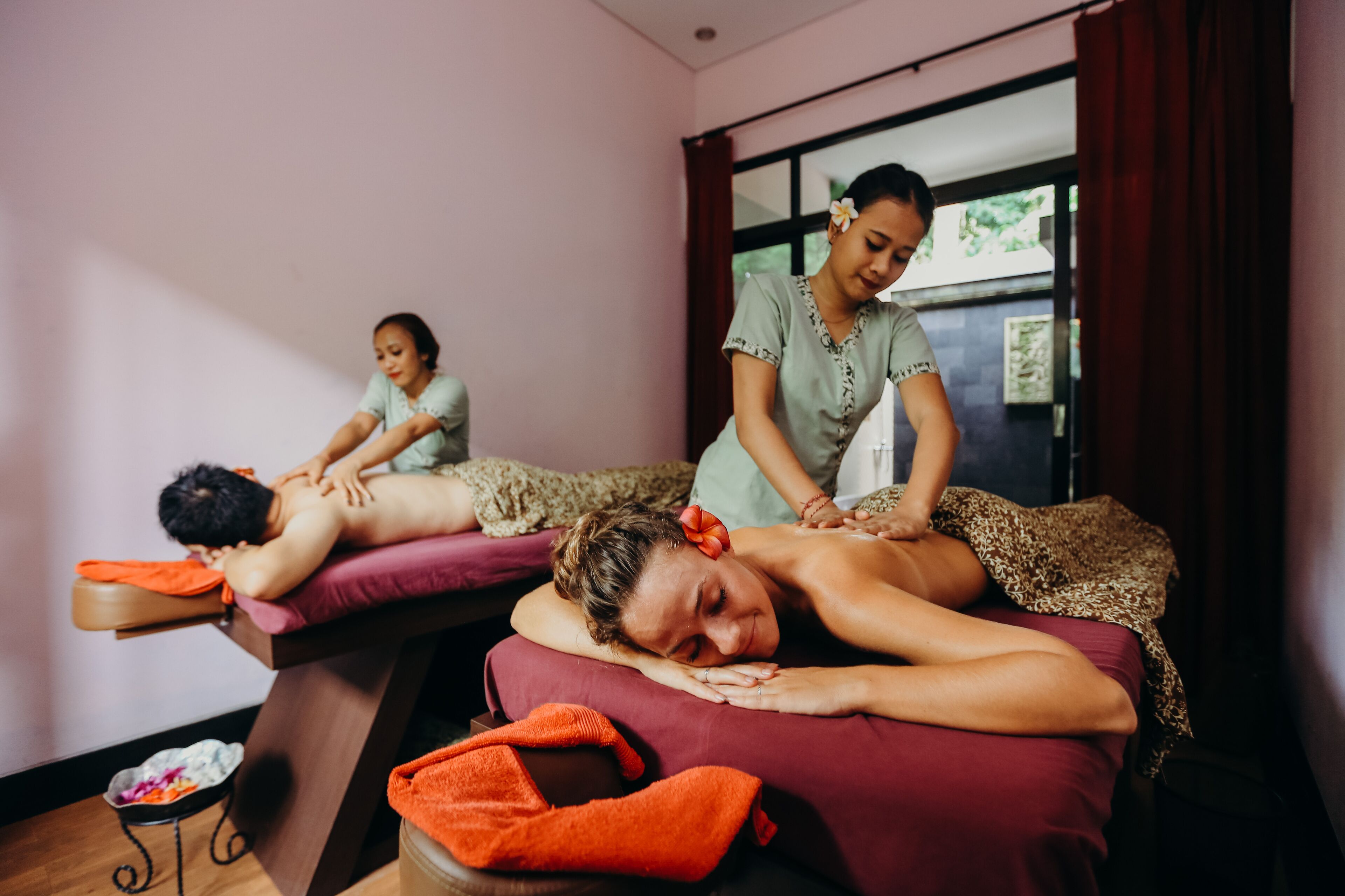 A massage therapy room with two massage tables, one occupied by a client and another by a therapist.