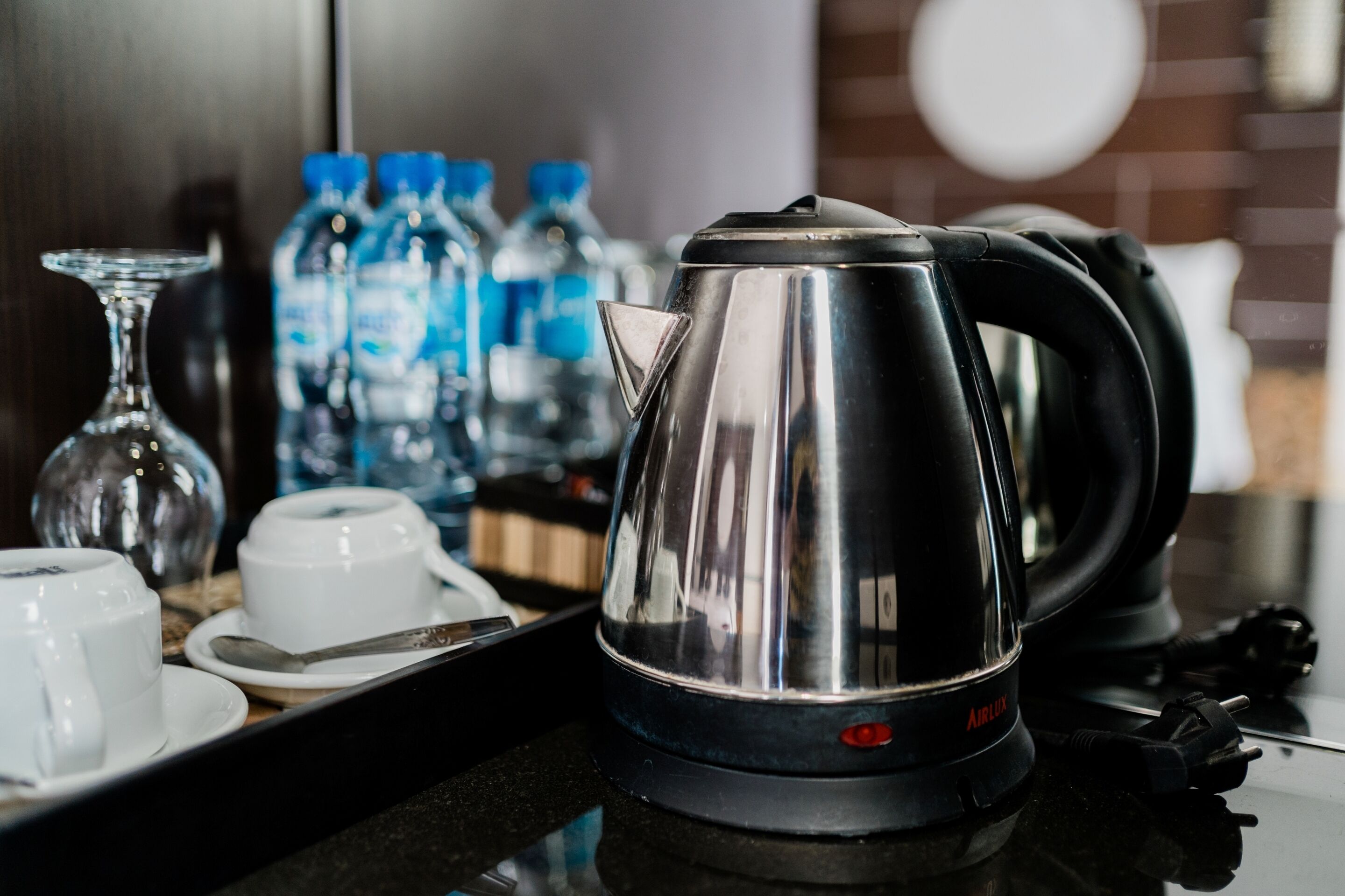 A kitchen counter with a kettle, cups, and water bottles.