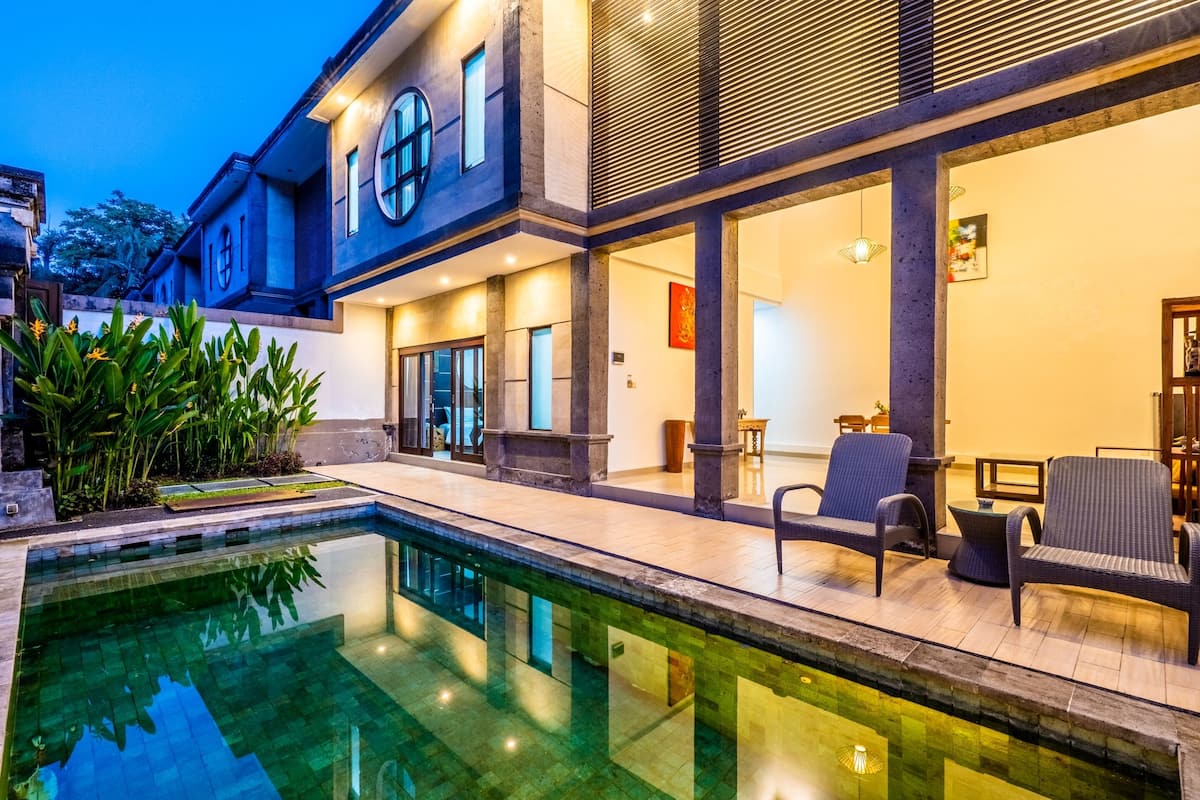 A modern house with a swimming pool, large windows, and outdoor seating.