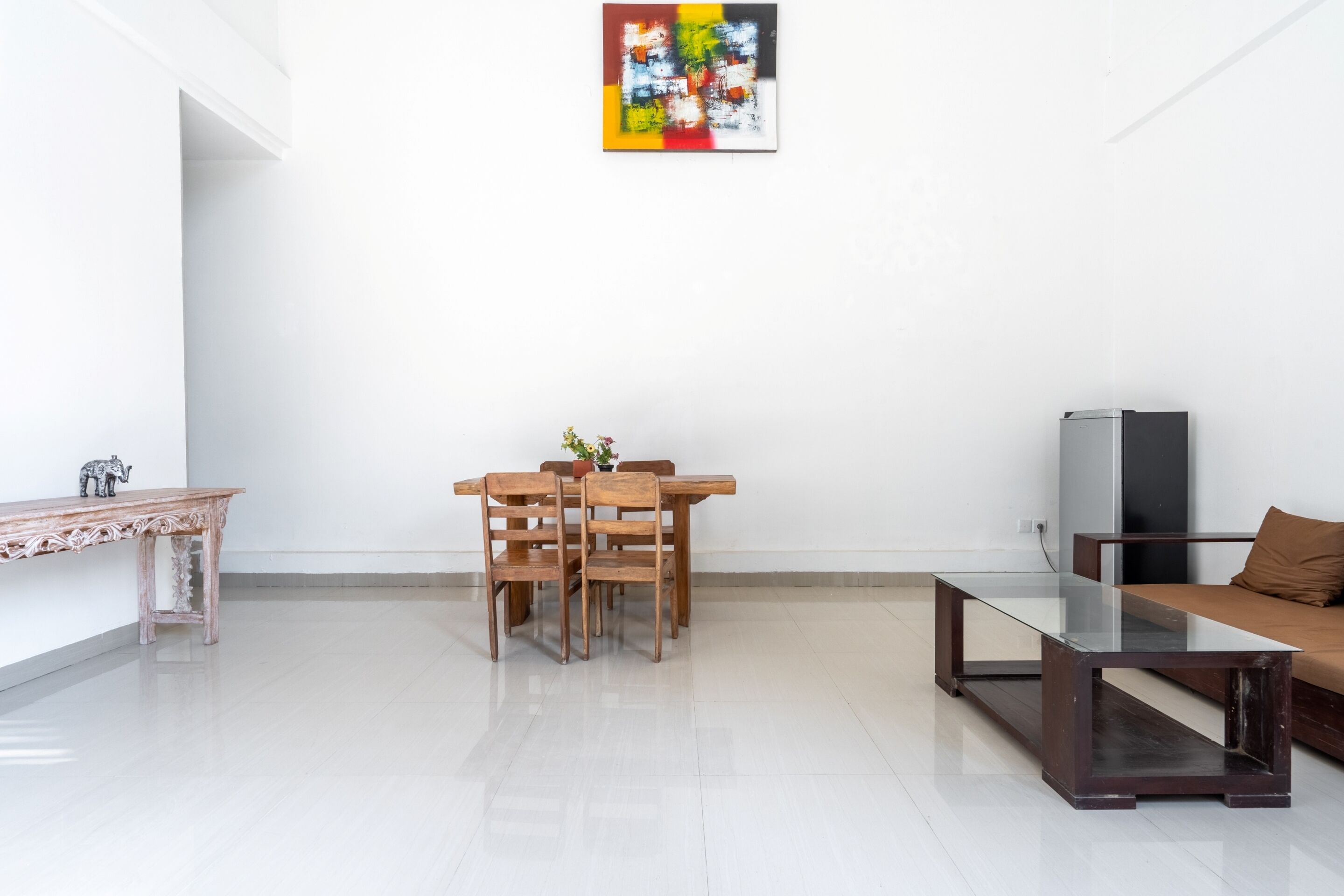 Una sala de estar moderna con una mesa de comedor de madera, sillas, una mesa baja de vidrio, un sofá y un televisor.