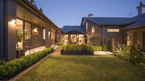 Una casa moderna con césped cuidado, zona de estar exterior y un porche cubierto.