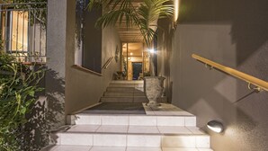 Una escalera con barandilla, una planta en maceta y una puerta al final.