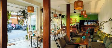 A cafe with wooden furniture, hanging lights, and a green wall with a menu.