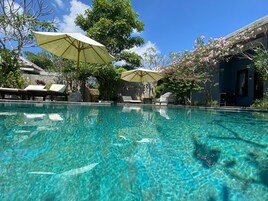 Una piscina al aire libre, sillones reclinables de piscina