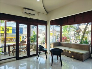 A spacious room with a large window, a sofa, and a chair. - Ashana Hotel Uluwatu (Pecatu)