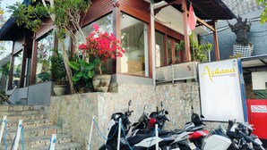 A hotel with a stone facade, a signboard, and parked motorcycles. - Ashana Hotel Uluwatu (Pecatu)