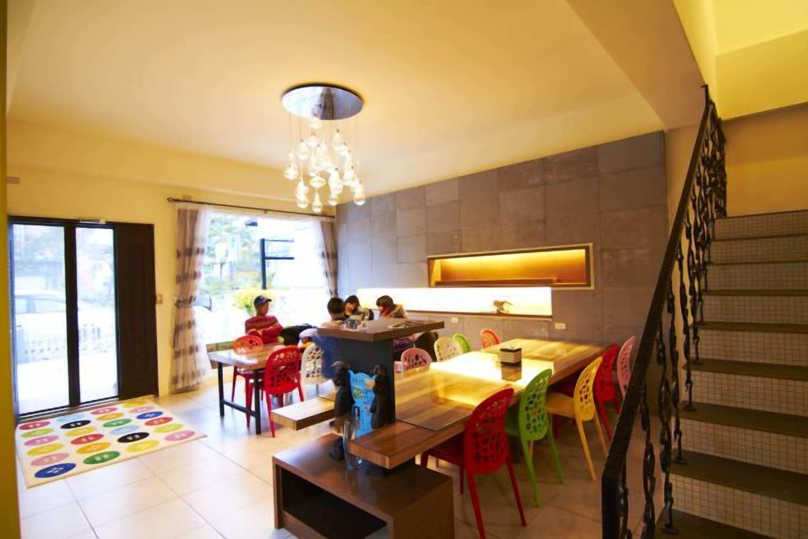 Un espace repas comprenant une table et des chaises, un lustre et un escalier.