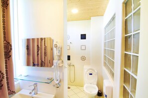 Un baño con cabina de ducha de vidrio, inodoro, lavabo con espejo y ducha.