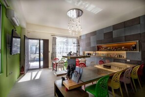 A modern kitchen with a dining area, featuring a central island, a chandelier, and a view through the glass door. - Locktaitung B&B (Taitung)