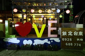 Entrada de hotel con un gran letrero con forma de corazón, un letrero que dice 'LOVE' y un letrero de neón con esferas de colores.