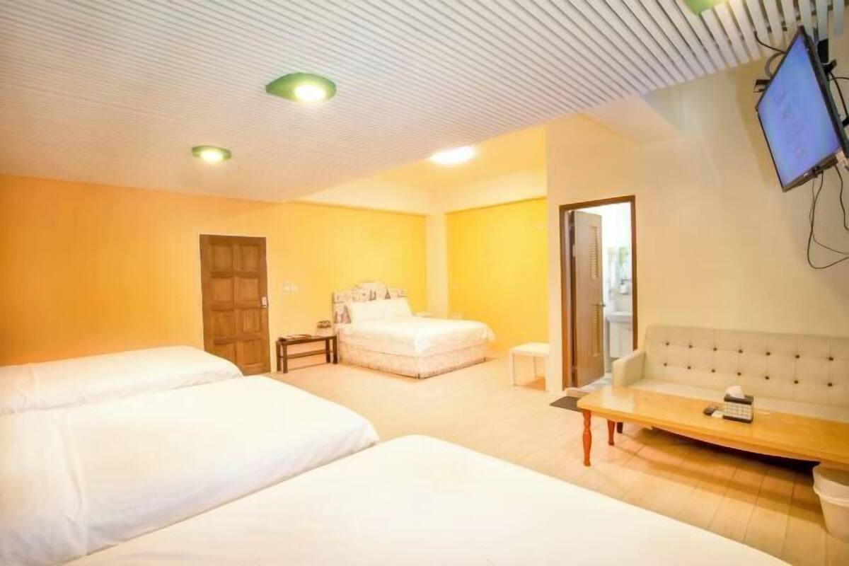 Une chambre d’hôtel avec deux lits, un canapé, une télévision et une porte donnant sur un balcon.