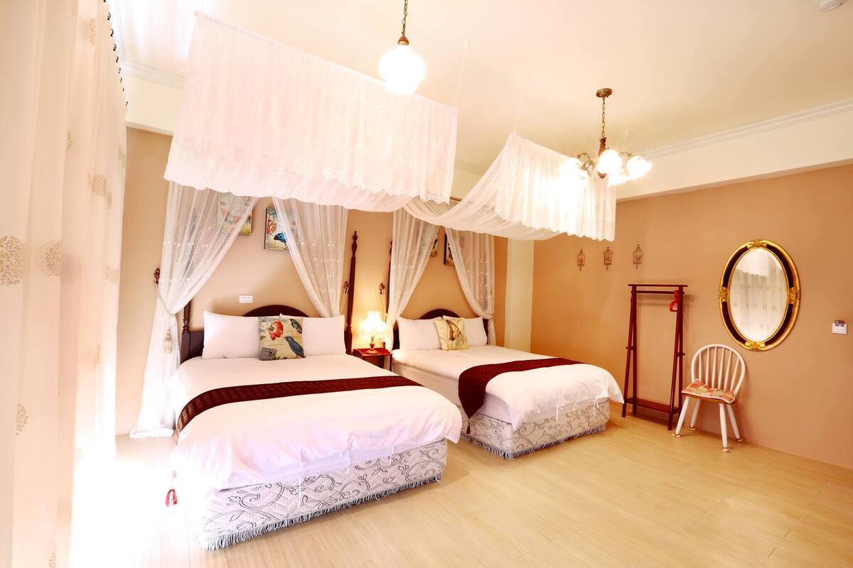 Une chambre avec deux lits, une chaise, un miroir et une table de chevet avec une lampe.