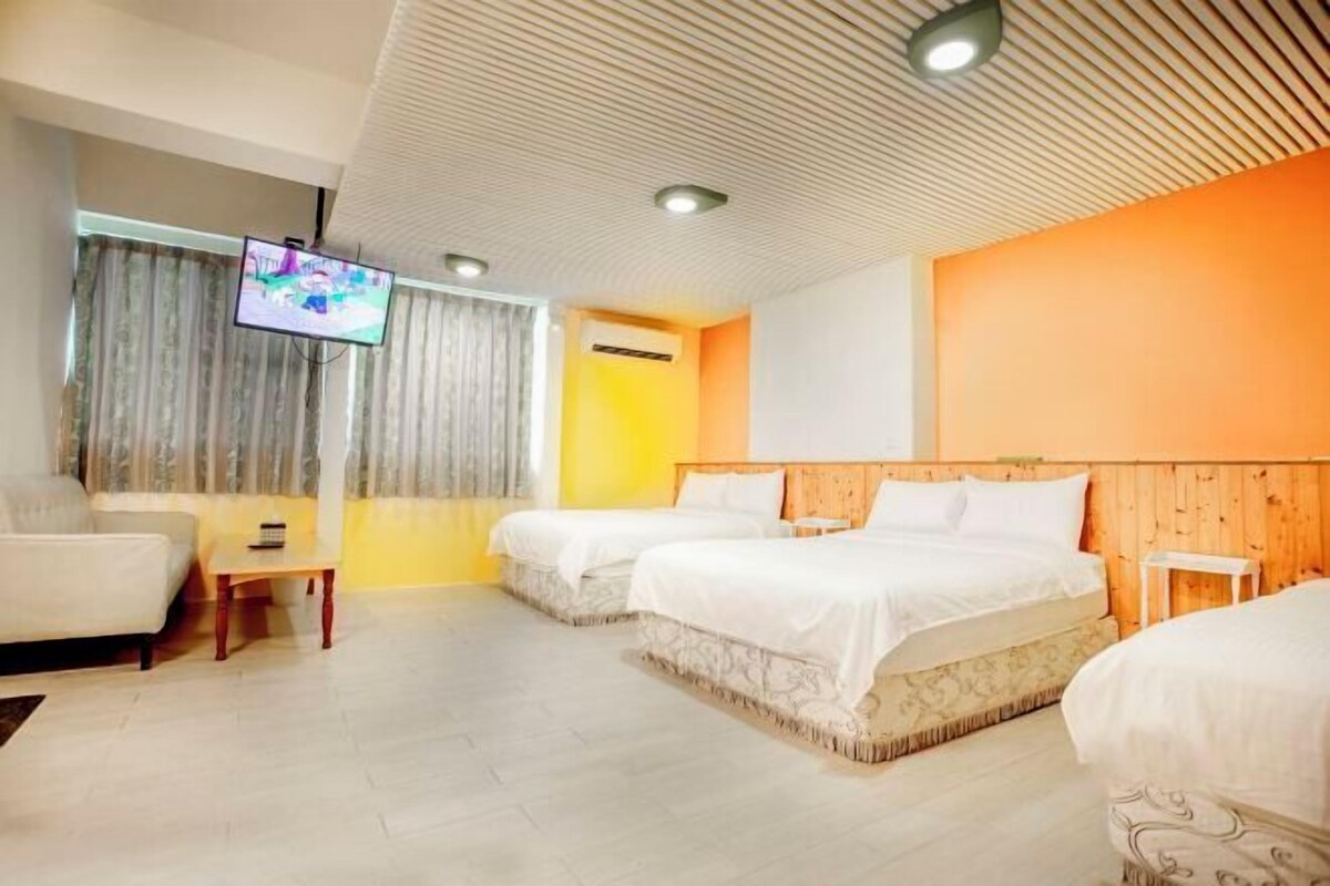 Habitación de hotel con dos camas, un sofá, un televisor y techo de madera.