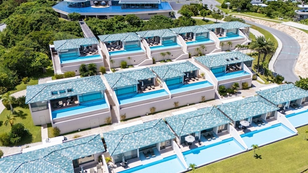 Un resort con varias piscinas conectadas por senderos, rodeado de abundante vegetación.