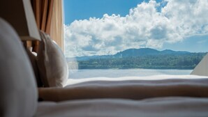 Una cama con vista a un lago y montañas.
