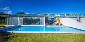 Eine moderne Villa mit Swimmingpool, großen Glasfenstern und einer Terrassenfläche.