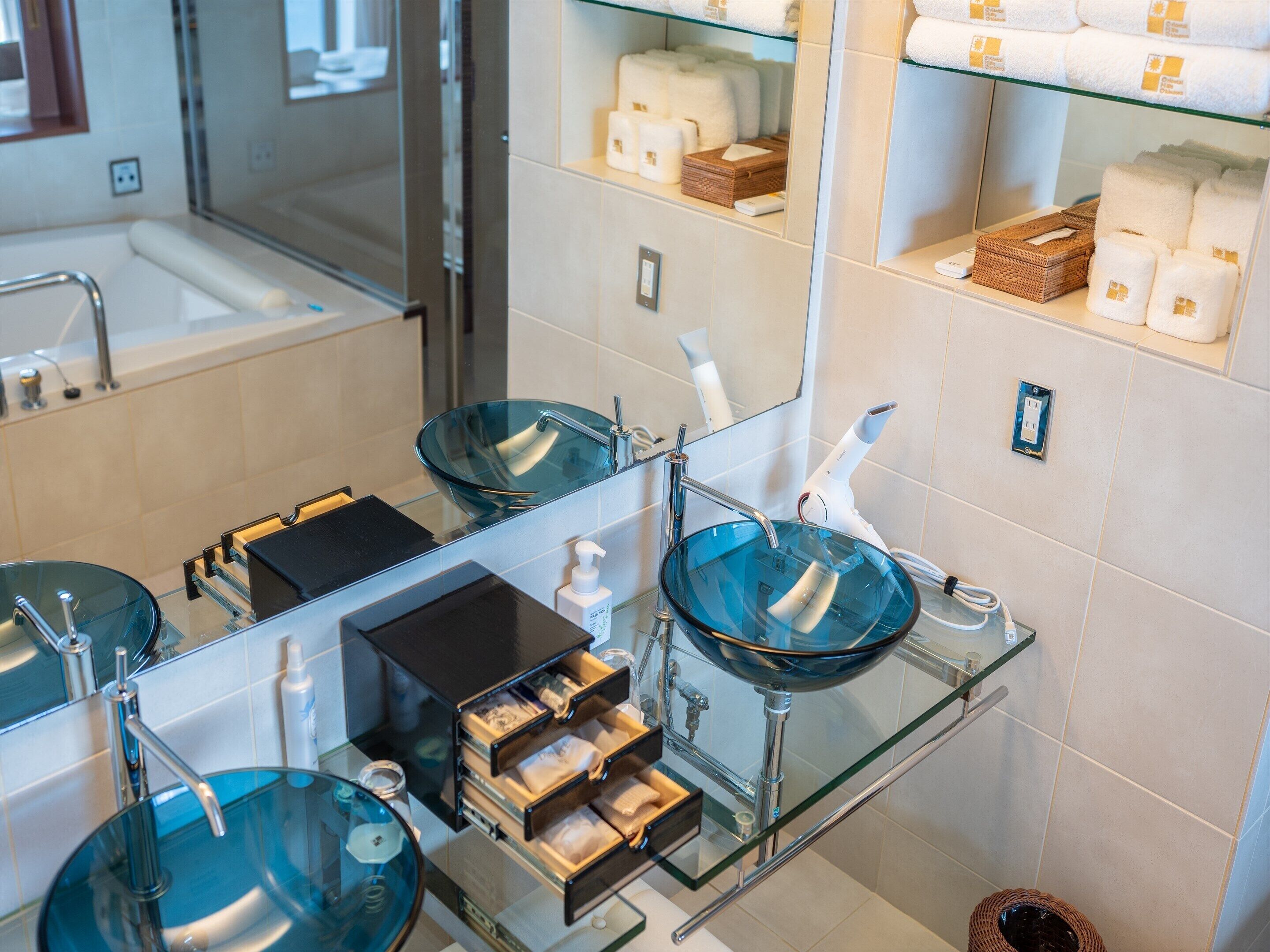 Un bagno moderno con lavandini in vetro, uno specchio e articoli da toilette sugli scaffali.
