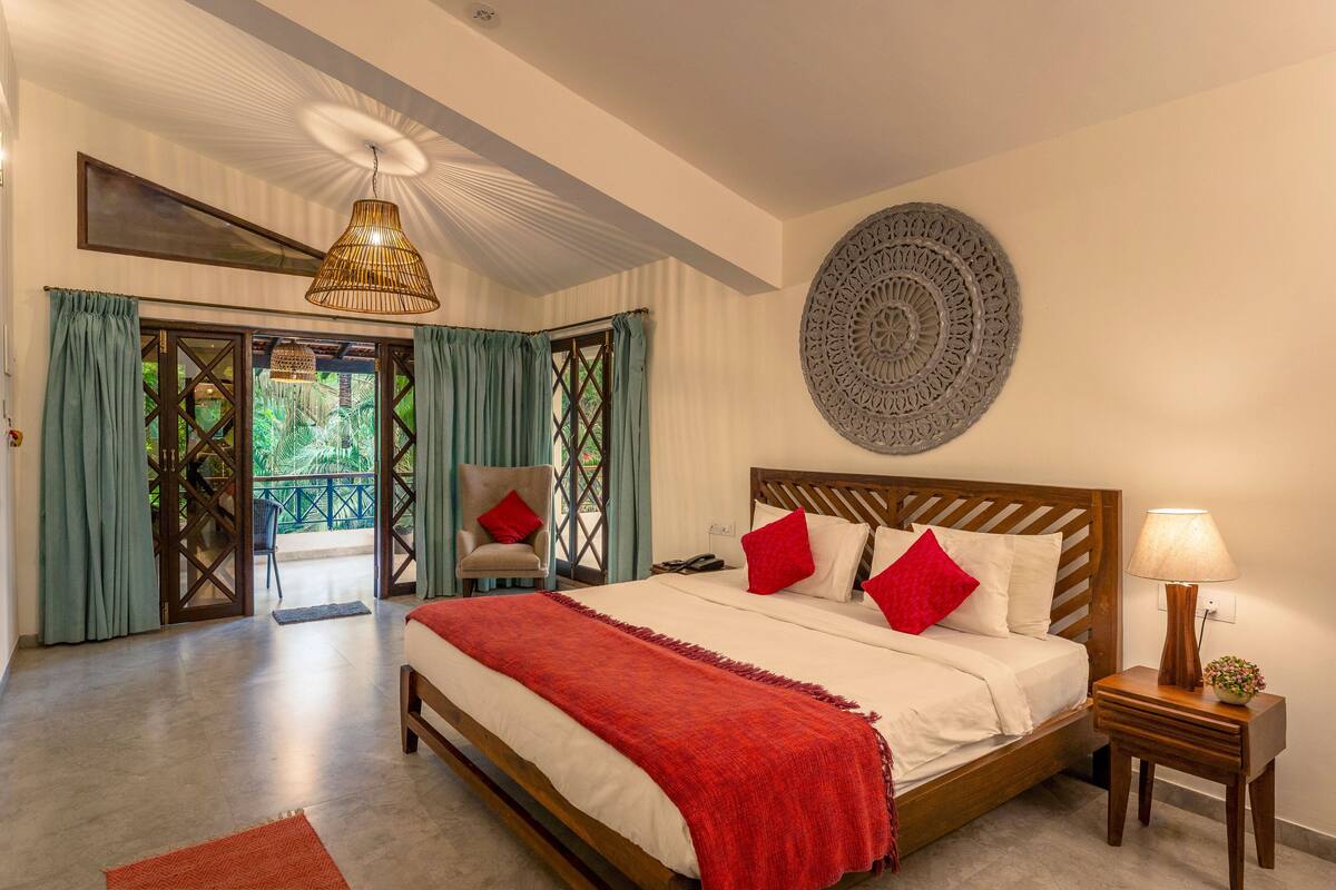 A bedroom with a large bed, a wooden headboard, a bedside table with a lamp, and a decorative wall piece.