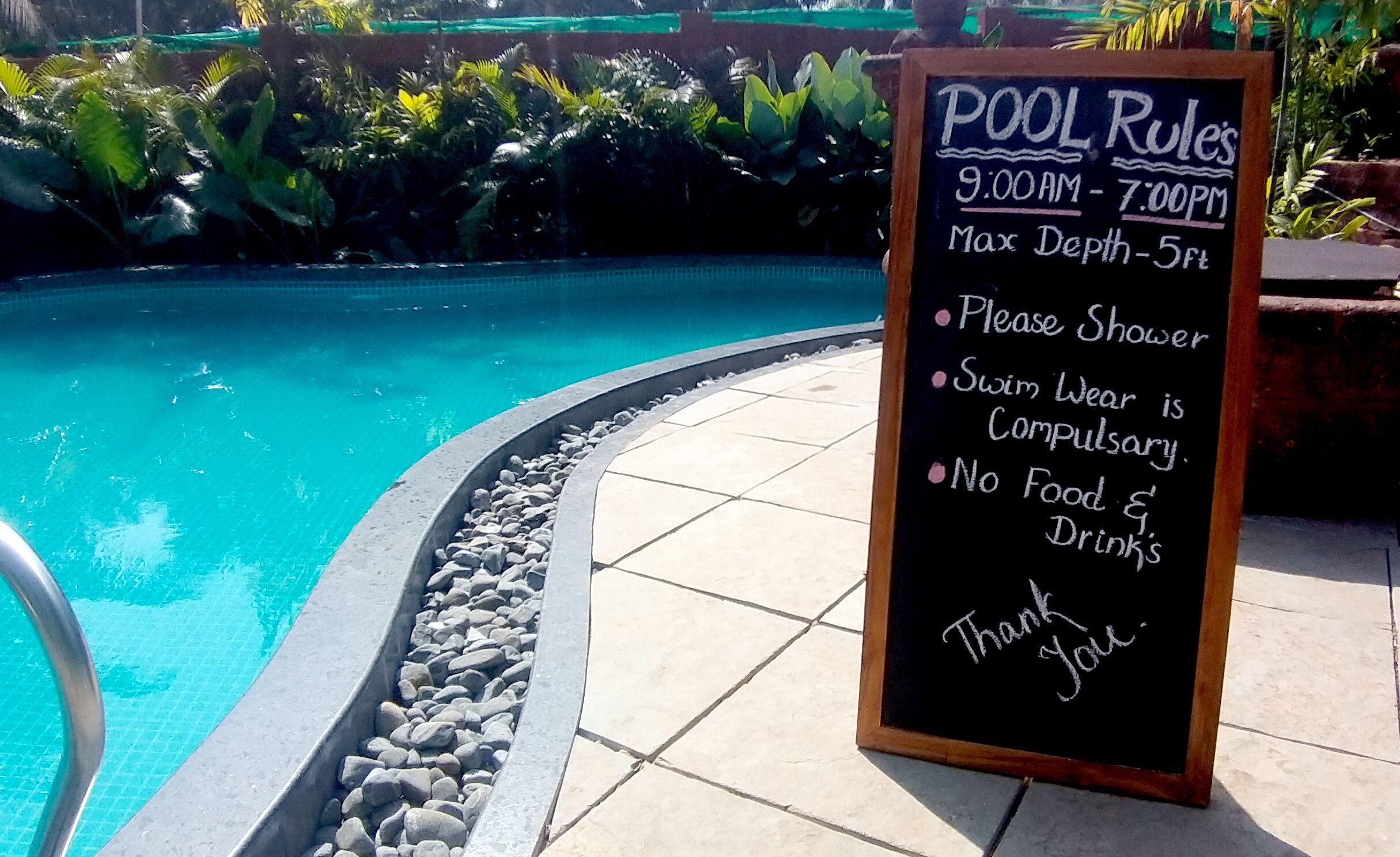 Placa à beira da piscina com regras e a própria piscina.
