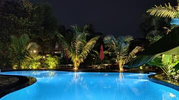 Una piscina al aire libre, sillones reclinables de piscina