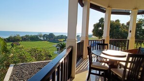 Een balkon met uitzicht op zee en groen.