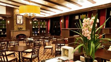 A hotel lobby with wooden furniture, a large yellow chandelier, and a fireplace.