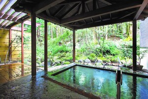 Piscina techada al aire libre con vistas a un jardín exuberante.