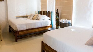 Ein Hotelzimmer mit zwei Betten, Holzbalken an der Decke, einem großen Fenster und einer Wand-Klimaanlage.