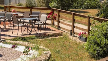 Un patio al aire libre con mesas y sillas, una cerca de madera y plantas en macetas.