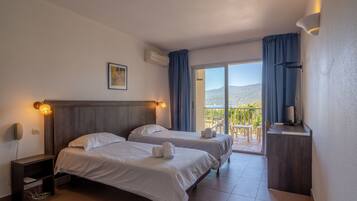 Habitación de hotel con dos camas, un escritorio, una silla y un balcón con vistas.
